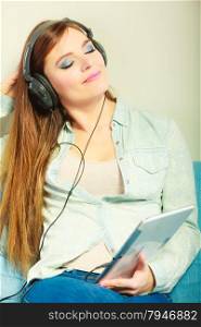 Modern technology leisure concept. Young attractive woman with headphones closed eyes relaxing using tablet