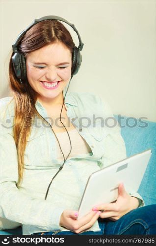 Modern technology leisure concept. Young attractive woman with headphones relaxing using tablet