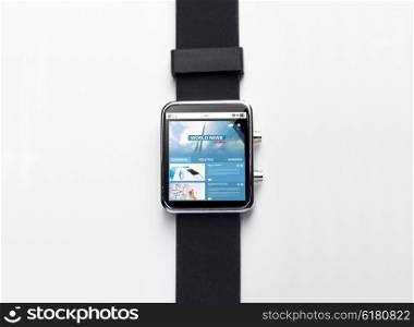 modern technology, object and mass media concept - close up of black smart watch with world news web page on screen