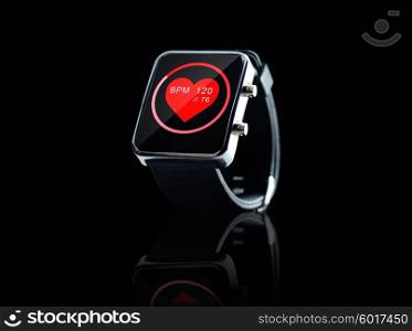 modern technology, object, health care and media concept - close up of black smart watch showing red heart beat icon on screen