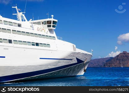 Modern tourist cruise ship sailing on Aegean sea, Santorini island, Greece. Sunny, blue sky.