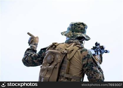 modern warfare soldier in action giving comands to team by hand signs while sneaking and aiming  on laseer sight optics  in combat position and  searching for target in battle
