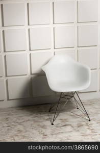 Modern white chair against white bricked wall
