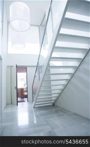 Modern white house entrance hall lobby with stairway and light coming in