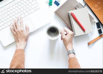 Modern white office desk table with businesswoman using laptop and drinking coffee