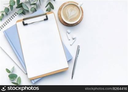 Modern white office desk table with coffee, notebook and other supplies. Blank copy space for  the text. Top view, flat lay.