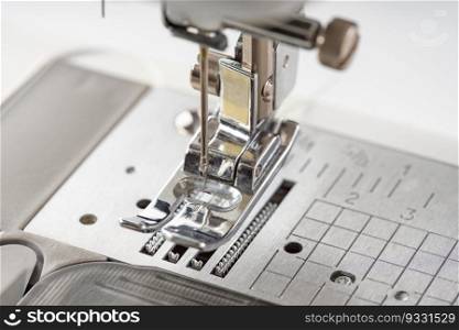 Modern white sewing machine presser foot closeup, macro. Sewing equipment, work tool for atelier business, manufacturing, occupation.