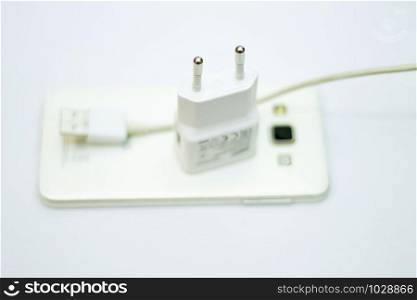 Modern white smartphone and phone charge with power cord isolated on the white bckground