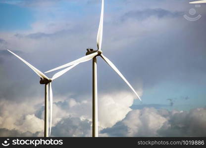 modern windmill on a sunny day and with idyllic moody clouds, closeup of the foreground, Energy concept