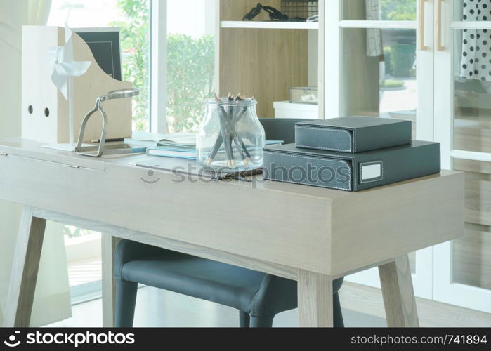 Modern wooden table with pencil, book and magnifying glass