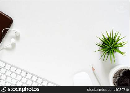 Modern workplace with wireless keyboard and mouse, a cup of coffee, smartphone with earphones, pencil and Tillandsia air plant on white background. Top view, flat lay concept.