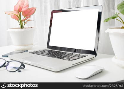 Modern workspace, mock up laptop computer blank white screen, eyeglasses and smartphone white table have potted plants on the desk, Notebook and mobile phone on desktop home office