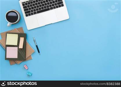Modern workspace with coffee cup, laptop, pen, paper, notebook, tablet and laptop copy space on blue color background. top view. flat lay style.