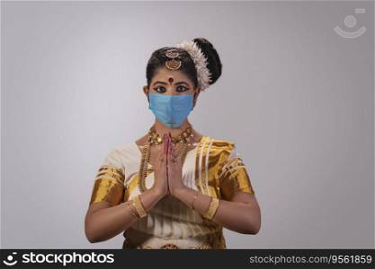 Mohiniattam dancer in a face mask greeting with her hands joined