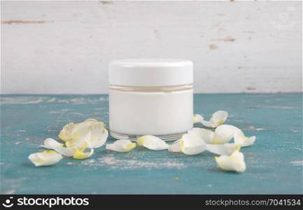 Moisturizer and rose petals on weathered background