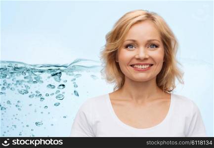 moisturizing and people concept - smiling woman in blank white t-shirt over blue background and water splash. smiling woman in blank white t-shirt