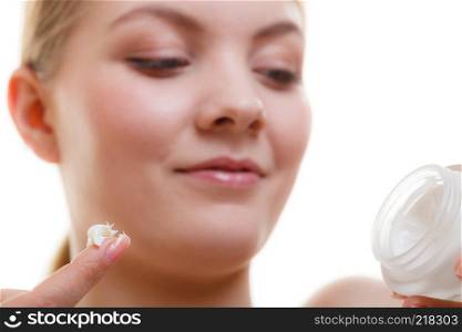 Moisturizing skin care, cosmetics, dermatology concept. Woman applying face cream with her finger, studio shot isolated. Woman applying face cream with her finger