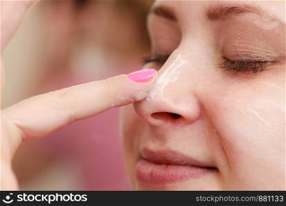 Moisturizing skin care, cosmetics, dermatology concept. Woman applying face cream with her finger. Woman applying face cream with her finger