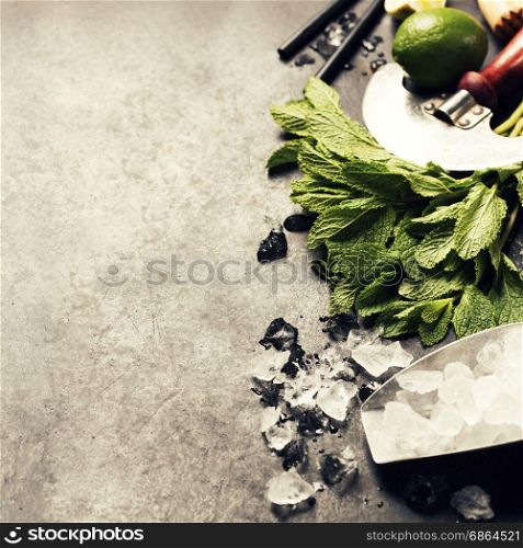 Mojito cocktail ingredients (fresh mint, lime, ice) on rustick background