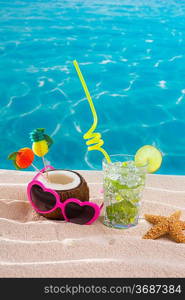 Mojito cocktail on beach sand with coconut and sunglasses in summer vacation