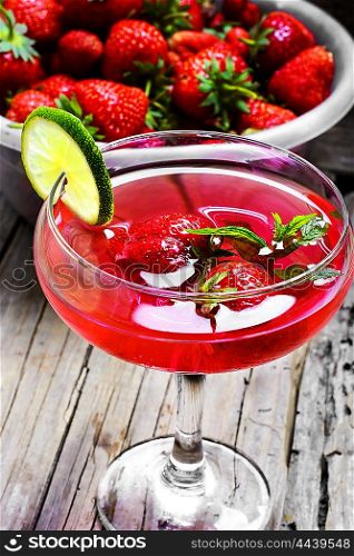 Mojito with lime and strawberry. alcohol cocktail in glass on a long stalk with strawberries and lime