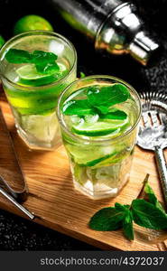 Mojito with pieces of lime and mint leaves. On a black background. High quality photo. Mojito with pieces of lime and mint leaves.