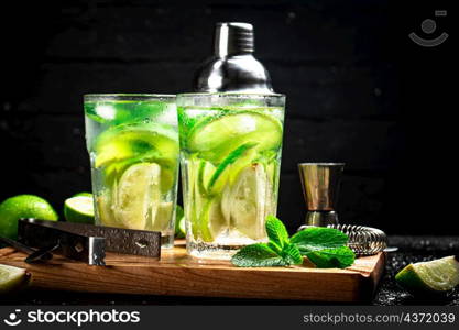 Mojito with pieces of lime and mint leaves. On a black background. High quality photo. Mojito with pieces of lime and mint leaves.