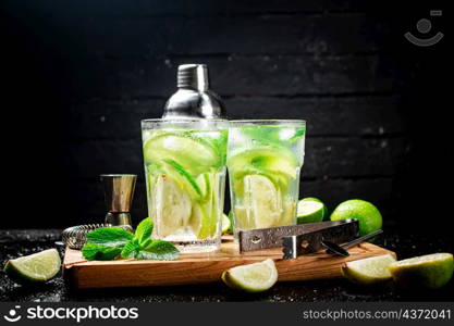 Mojito with pieces of lime and mint leaves. On a black background. High quality photo. Mojito with pieces of lime and mint leaves.