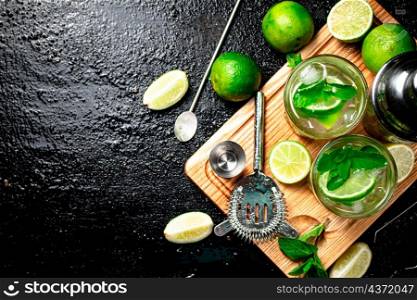Mojito with pieces of lime and mint leaves. On a black background. High quality photo. Mojito with pieces of lime and mint leaves.