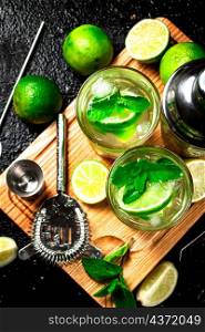 Mojito with pieces of lime and mint leaves. On a black background. High quality photo. Mojito with pieces of lime and mint leaves.