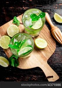 Mojito with pieces of lime on a cutting board. On a rustic dark background. High quality photo. Mojito with pieces of lime on a cutting board.