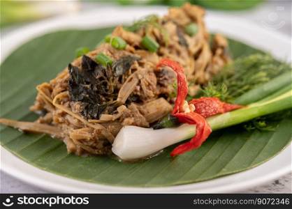 Mok bamboo shoots, put the pork on the banana leaf on a white plate. Thai food.