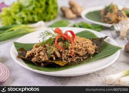 Mok bamboo shoots, put the pork on the banana leaf on a white plate. Thai food.