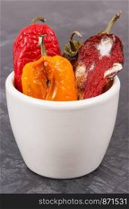 Moldy and wrinkled peppers in white bowl. Concept of unhealthy, decompose, spoiled vegetable. Moldy and wrinkled peppers in white bowl. Unhealthy, decompose, spoiled vegetable