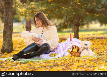 Mom and baby on a picnic in the city park in the autumn