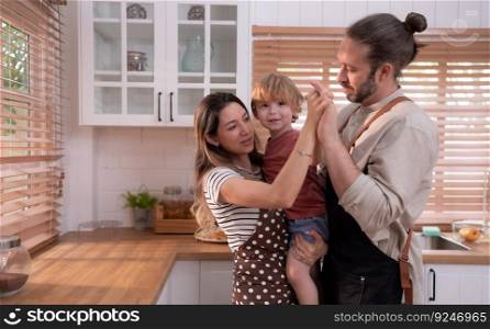 Mom and dad in the kitchen of the house with their small children. Have a good time making dinner together.