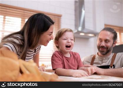 Mom and dad in the kitchen of the house with their small children. Have a good time baking bread and making dinner together.