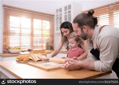 Mom and dad in the kitchen of the house with their small children. Have a good time baking bread and making dinner together.