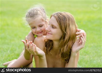 Mom and daughter having fun embrace the summer picnic on a green lawn