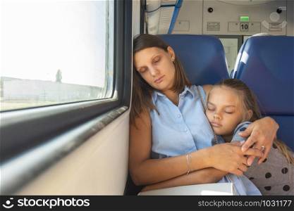 Mom and daughter hugging sleeping in a train car