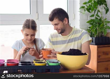 Mom and daughter plant seedlings in flower pots