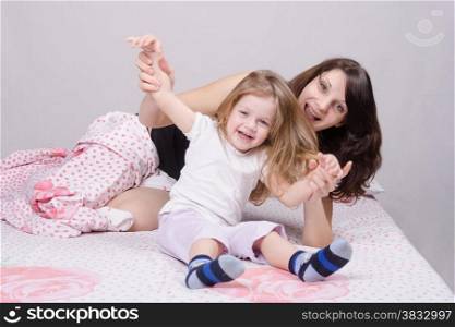 Mom and daughter with an excellent mood sitting on the bed