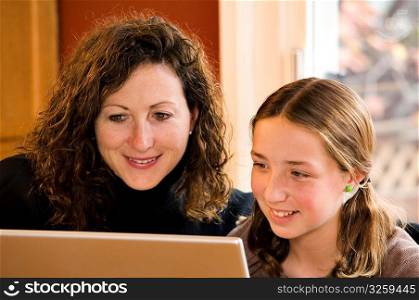 Mom and daughter working on computer laptop.