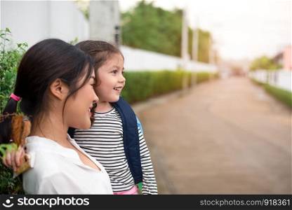 Mom and her daughter smiling together after going home from school. Love and daycare concept. Happy family and Home sweet home theme.