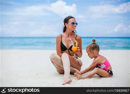 Mom and her little cuty baby girl on the beach vacation. Adorable little girls and young mother on tropical white beach
