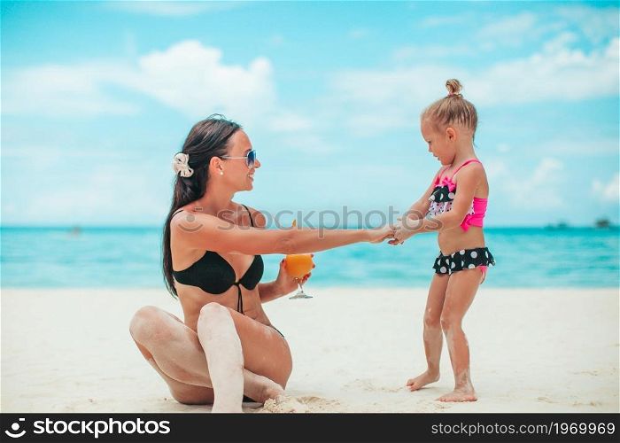 Mom and her little cuty baby girl on the beach vacation. Adorable little girls and young mother on tropical white beach