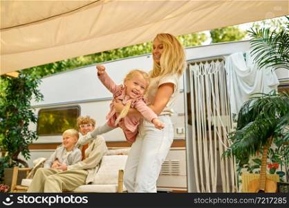 Mom and her little girl having fun at the trailer, summer camping. Family with kids travel in camp car, nature and forest on background. Campsite adventure, travelling lifestyle, campers. Mom and her little girl having fun at the trailer