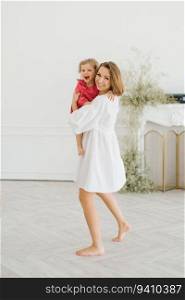 Mom and little daughter have fun in the bright living room of the house