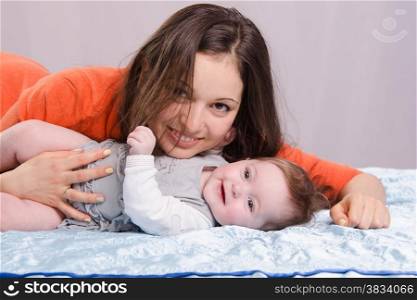 Mom and six-month daughter happily lie on the couch