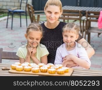 Mom and two daughters sitting at a table on which lay cooked them Easter cupcakes